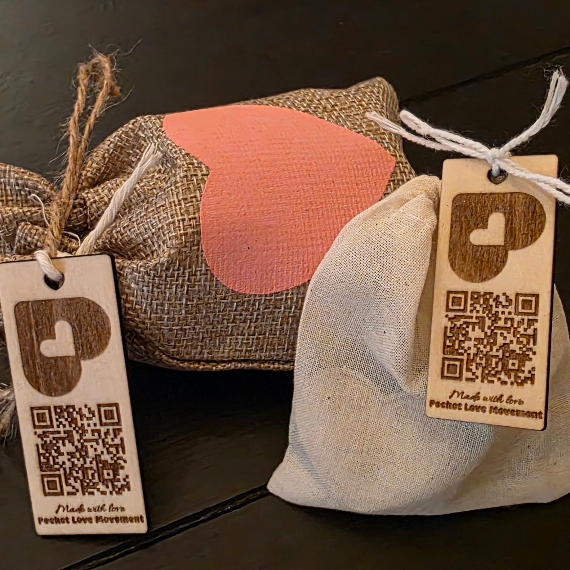 Two small bags with pocket hugs and  decorative pocket love movement tags on a dark surface