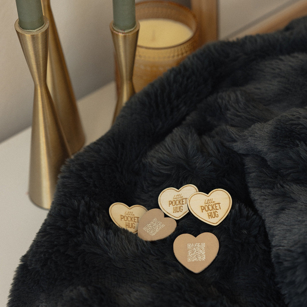 Heart-shaped tokens on a black minky blanket surface with candles and a mirror in the background.